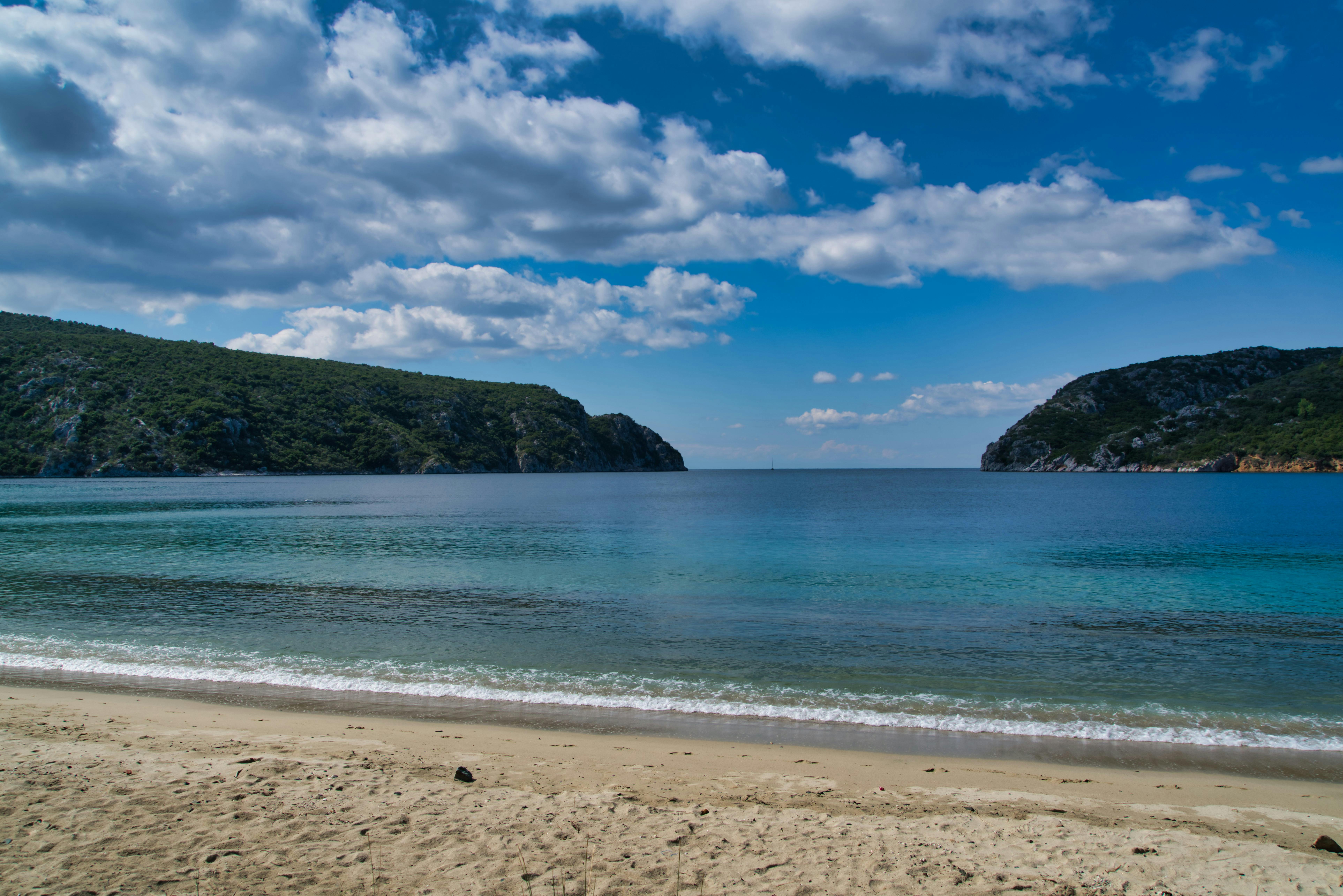 Peaceful Greek beach scene with turquoise waters and a clear blue sky, ideal for summer vacations.