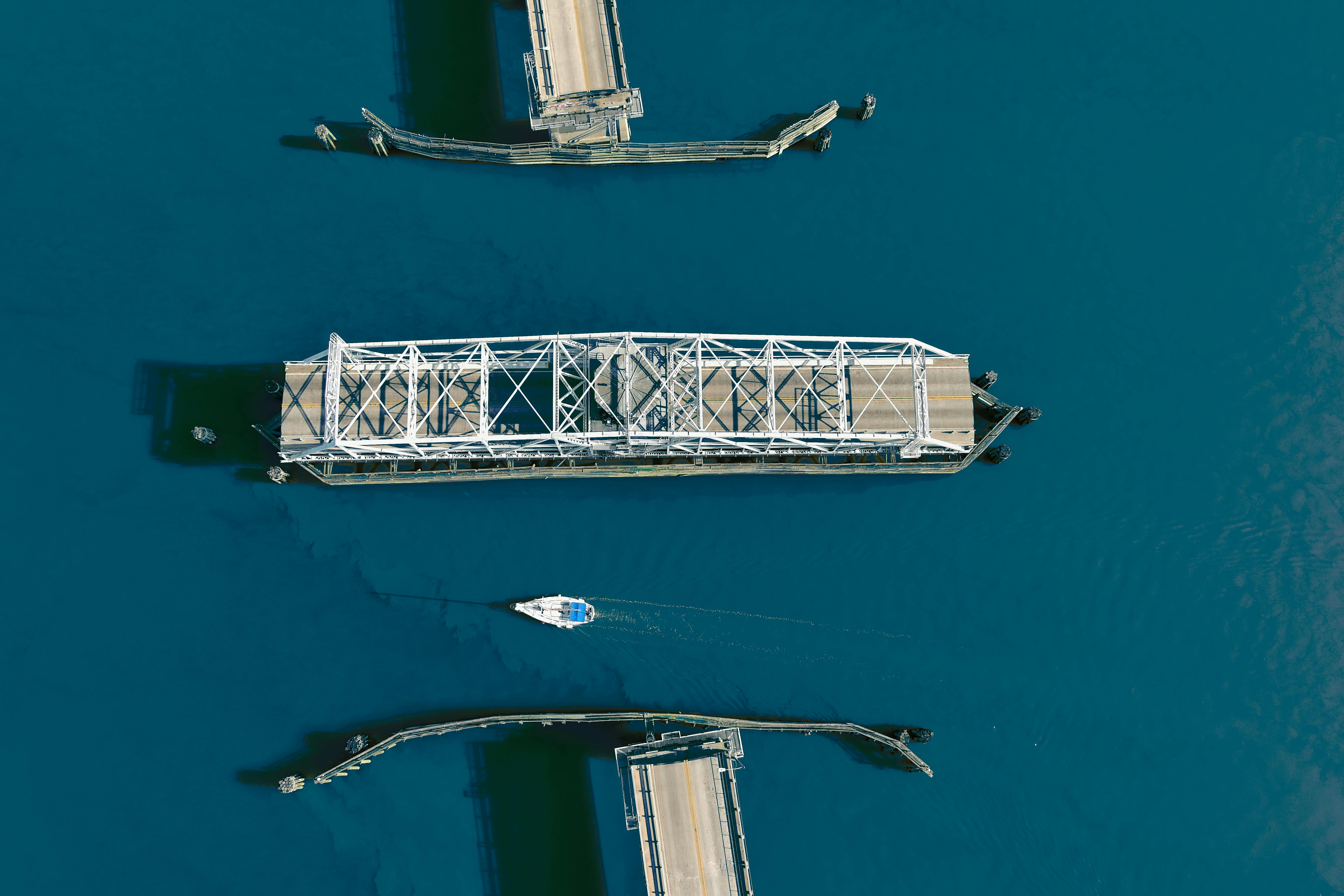 Aerial shot of a swing bridge opening over a strait with a sailing boat below, located in Beaufort, SC.